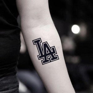 May include: A black and white temporary tattoo of the LA Dodgers logo.