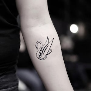 Puede incluir: Un tatuaje temporal de línea negra de un cisne con las alas extendidas.