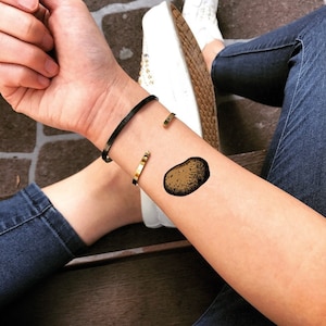 May include: A temporary tattoo of a brown potato on a person's wrist.