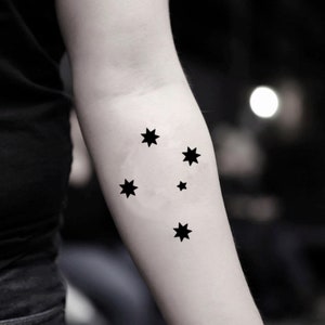 May include: A black temporary tattoo of the Southern Cross constellation, a group of five stars, on a person's arm.