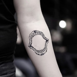 May include: A black and white temporary tattoo of a shark's jaw with teeth.