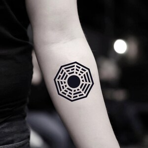 May include: A black and white temporary tattoo of the Dharma Initiative symbol from the TV show Lost.