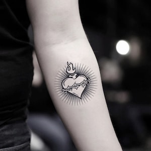 May include: Black and white temporary tattoo of a heart with a crown of thorns and a flame on top.