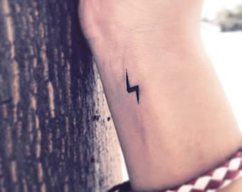 May include: A small black lightning bolt tattoo on a person's wrist.