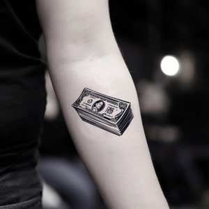 May include: A black and white temporary tattoo of a stack of US dollar bills.