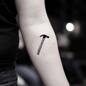 May include: A black and white temporary tattoo of a hammer.