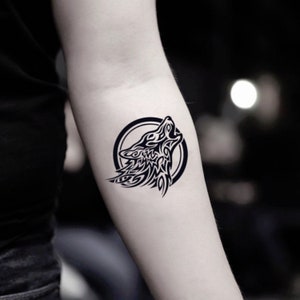 May include: Black and white tribal wolf tattoo design. The wolf is howling and is surrounded by a circle.