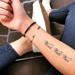 May include: A temporary tattoo on a person's arm with the Latin phrase "Veni Vidi Vici" in cursive script.