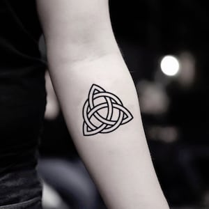 May include: A black and white temporary tattoo of a Celtic knot design. The knot is in the shape of a triangle with three interlocking circles.