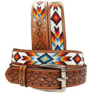 Op de afbeelding: Een bruine leren riem met een kralenontwerp met geometrische patronen in rood, oranje, blauw en wit. De riem heeft een zilveren gesp.