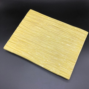 Könnte beinhalten: Ein gelbes Keramik-Serviertablett mit einem strukturierten Bambus-Design.