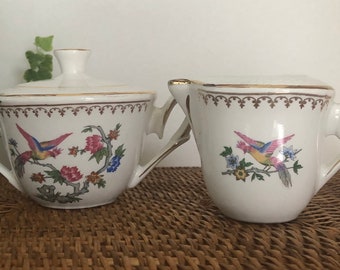 Vintage Saint Amand L' Amandinoise Paradise pottery set of milk jug and sugar bowl. Flowers and bird of paradise images. France 1950's.