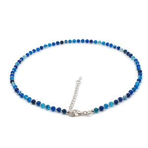 Beaded blue Agate necklace, made with 4 mm round gemstone beads interspaced with 2 mm silver plated glass beads, strung on flexible silicon plated steel beading wire. Finished with silver plated brass lobster claw clasp and extension chain.