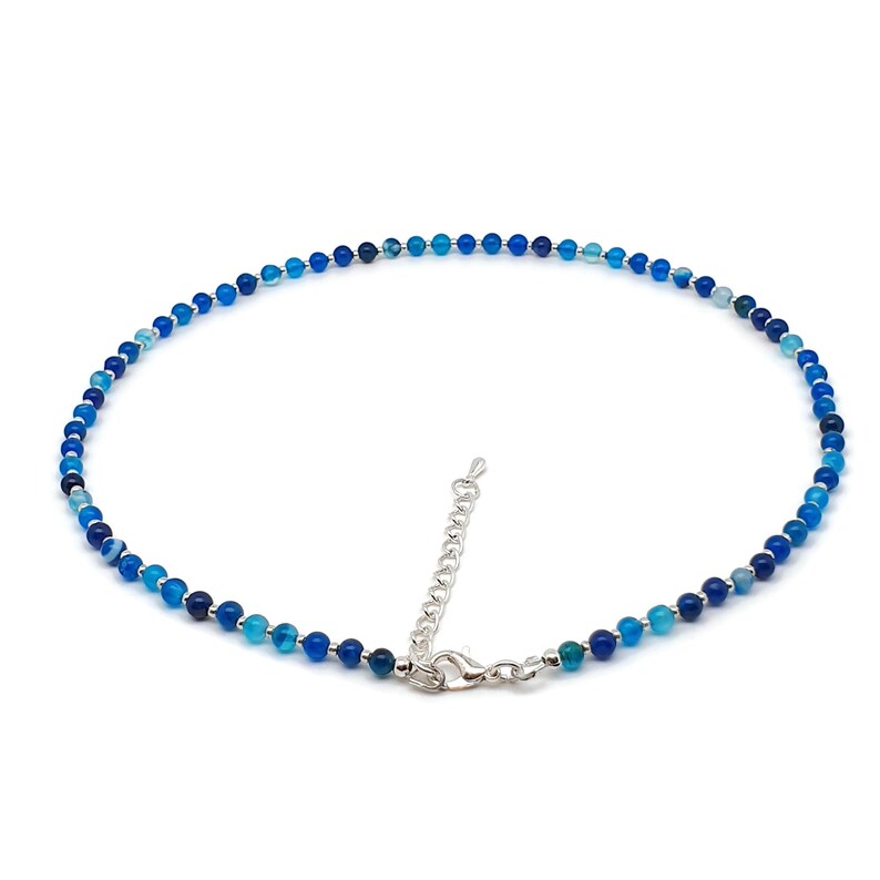 Beaded blue Agate necklace, made with 4 mm round gemstone beads interspaced with 2 mm silver plated glass beads, strung on flexible silicon plated steel beading wire. Finished with silver plated brass lobster claw clasp and extension chain.