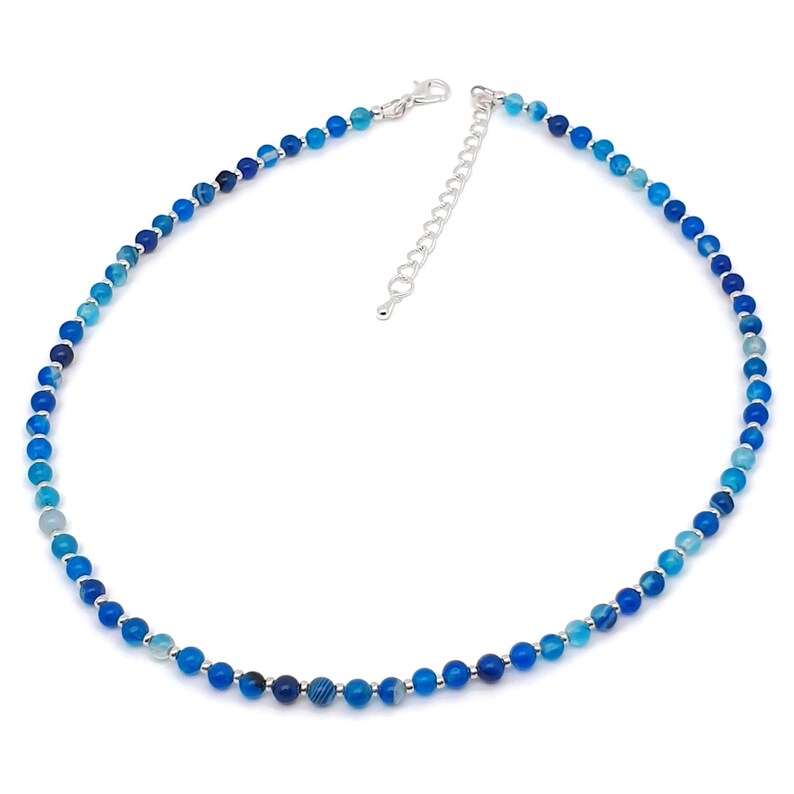 Beaded blue Agate necklace, made with 4 mm round gemstone beads interspaced with 2 mm silver plated glass beads, strung on flexible silicon plated steel beading wire. Finished with silver plated brass lobster claw clasp and extension chain.