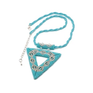 May include: A turquoise beaded necklace with a triangular pendant. The pendant features a silver beaded design within the triangle. The necklace has a twisted rope design and a silver chain for adjusting the length.