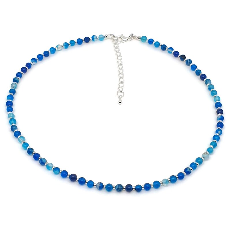 Beaded blue Agate necklace, made with 4 mm round gemstone beads interspaced with 2 mm silver plated glass beads, strung on flexible silicon plated steel beading wire. Finished with silver plated brass lobster claw clasp and extension chain.