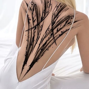 May include: A person with a black abstract tattoo on their back. The tattoo is made up of a series of lines and shapes that create a dynamic and eye-catching design.