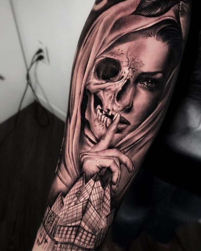 May include: Black and white tattoo design of a woman's face with a skull overlay. The woman's face is partially obscured by a hood, and she is holding her finger to her lips in a gesture of silence. The tattoo is on a person's arm.