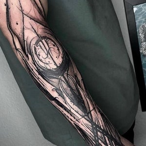 May include: Black and white abstract tattoo design on a person's forearm. The design features intricate lines and swirls.
