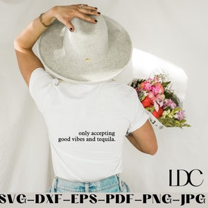 May include: A white t-shirt with the text "only accepting good vibes and tequila." printed on the back. The shirt is being worn by a person with a white hat and holding a bouquet of flowers.