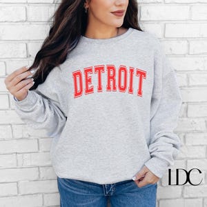 May include: A gray sweatshirt with the word "DETROIT" printed in red letters.