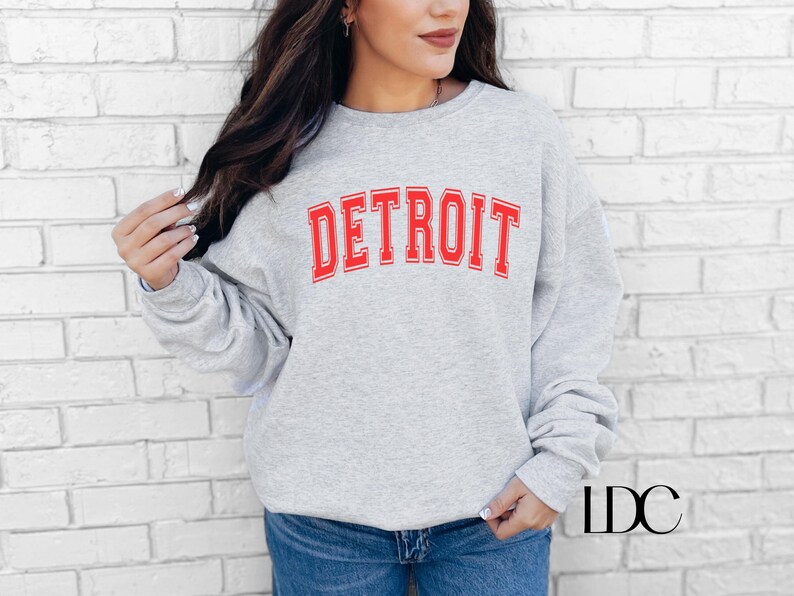 May include: A gray sweatshirt with the word "DETROIT" printed in red letters.