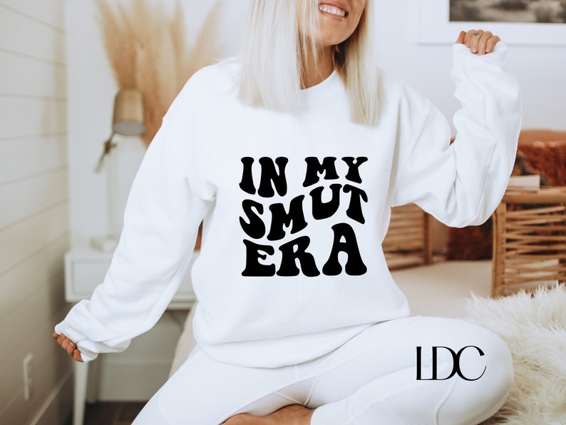 May include: White sweatshirt with black text that reads "In My Smut Era" in a retro font.