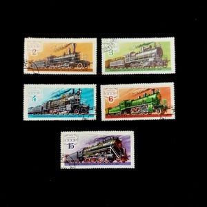 Può includere: Una collezione di cinque francobolli rettangolari dell'URSS, ognuno con un'illustrazione dettagliata di una locomotiva a vapore. I francobolli sono stampati in vari colori tra cui arancione, verde, blu e viola, con testo e numeri in cirillico.