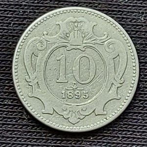 Pode incluir: Uma moeda circular de cor prateada com o número 10 em destaque no centro e o ano 1895 inscrito logo abaixo. A moeda é rodeada por uma borda decorativa ornamentada com um design de contas ao longo de todo o contorno exterior.