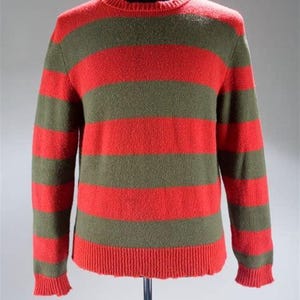May include: A red and green striped sweater with a crew neck. The sweater has a distressed look with frayed edges.