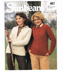 May include: Two women wearing knitted sweaters. The woman on the left is wearing a white sweater with a cable knit pattern. The woman on the right is wearing a red sweater with a cable knit pattern. The image includes the text "Sunbeam" and "467 Aran 86-102 cm bust 34-40 ins".