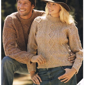 May include: Two sweaters in a cable knit pattern, one brown and one beige, with a brown hat and a brown fedora. The sweaters are made with Donegal Tweed DK yarn. The image includes the text "Donegal Tweed DK", "Sirdar", "8455", "81-112cm 32-44", and "for mans hat pattern see leaflet No. 8436".