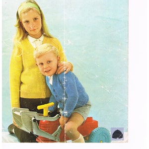 May include: A knitting pattern booklet featuring two children wearing knitted cardigans. The girl is wearing a yellow cardigan and the boy is wearing a blue cardigan. The pattern is for "Double Knittings by Patons or Patons Brilliante Double Knitting". The pattern is for sizes 2-13 years, 22-32 inch chest. The pattern number is 9461 and the price is 9d.