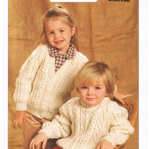 May include: Two children wearing cream-colored Aran knit sweaters. The sweaters have a cable knit design. The image includes text that reads "Aran Knitting" and "Patons Wool Boutique". The sweaters are sized 20-30 inches.