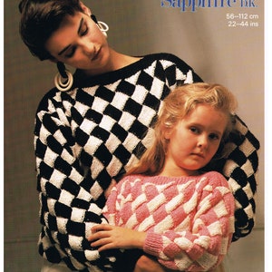 Könnte beinhalten: Eine Frau und ein Mädchen tragen schwarz-weiß karierte Pullover. Die Frau trägt große Creolen. Das Mädchen trägt einen rosa-weiß karierte Pullover. Der Text "Sunbeam 1236 Sapphire DK. 56-112 cm 22-44 ins" ist in der oberen rechten Ecke des Bildes sichtbar.