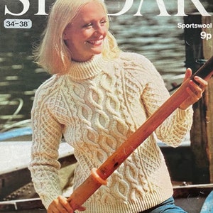 May include: A white cable knit sweater with a turtleneck collar. The sweater is being worn by a person holding a wooden oar. The image is from a vintage knitting pattern.
