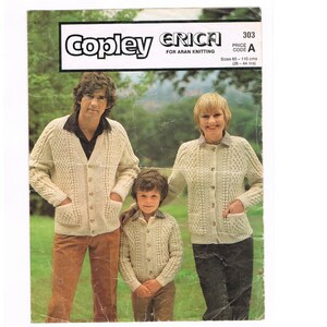May include: A knitting pattern booklet featuring three people wearing cream-colored cardigans. The booklet cover has the title "Copley Erica" and the text "For Aran Knitting" and "Price Code A".