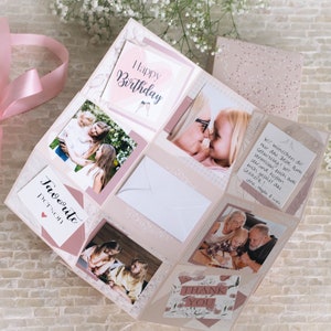 Puede incluir: Un álbum de recortes rosa y blanco con fotos y mensajes escritos a mano. El álbum tiene una cinta rosa atada alrededor. El texto en el álbum dice "Feliz cumpleaños" y "Gracias".