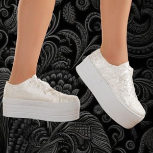 Può includere: Sneakers bianche con piattaforma, chiusura con lacci e motivo floreale. Le sneakers hanno una suola spessa in piattaforma bianca.