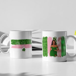 Puede incluir: Dos tazas de cerámica blanca con un diseño verde y rosa. Una taza presenta una mujer con un vestido verde con el texto "Oh So Pretty" y un trébol verde. La otra taza presenta un diseño abstracto verde y rosa.