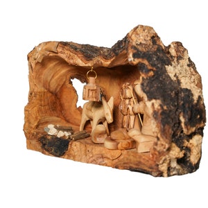 May include: A wooden nativity scene carved from a tree trunk. The scene includes a donkey, a shepherd, and a lantern hanging from the top of the trunk.