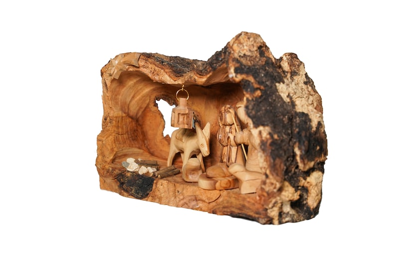 May include: A wooden nativity scene carved from a tree trunk. The scene includes a donkey, a shepherd, and a lantern hanging from the top of the trunk.