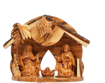 May include: A carved olive wood nativity scene featuring a stable structure with a palm tree and a star. The figures include a central infant in a manger, flanked by two adult figures, a cow, and a donkey. The text Saint Michael is at the bottom.