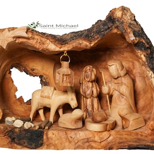 May include: A hand-carved nativity scene set inside a hollowed-out olive wood log. The scene includes Mary, Joseph, a donkey, a lamb, and a star.