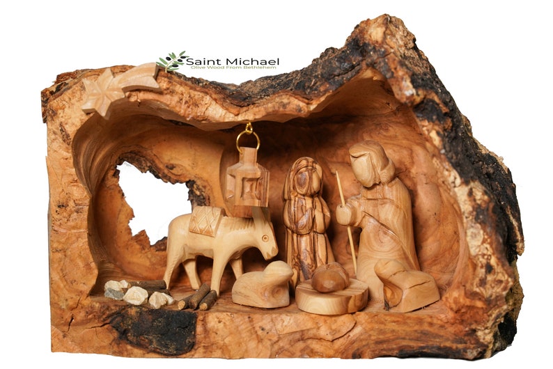 May include: A hand-carved nativity scene set inside a hollowed-out olive wood log. The scene includes Mary, Joseph, a donkey, a lamb, and a star.