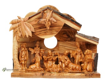 May include: A hand-carved olive wood nativity scene with a star on top and a palm tree on the side. The scene includes the baby Jesus, Mary, Joseph, and the three wise men.