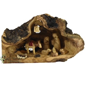May include: A hand-carved olive wood nativity scene set inside a hollowed-out olive wood log. The scene includes Mary, Joseph, baby Jesus, a donkey, a sheep, and a lantern.