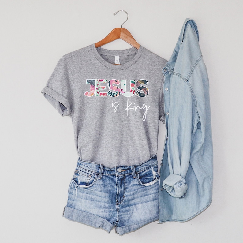May include: A gray t-shirt with a floral design that spells out "JESUS is King" in white text.