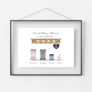 May include: Framed print with the text "And then there were four...". The artwork features a wooden shelf with hooks and heart cutouts, and illustrations of four pairs of wellington boots: pink floral, grey, blue, and pink. Names are written below.